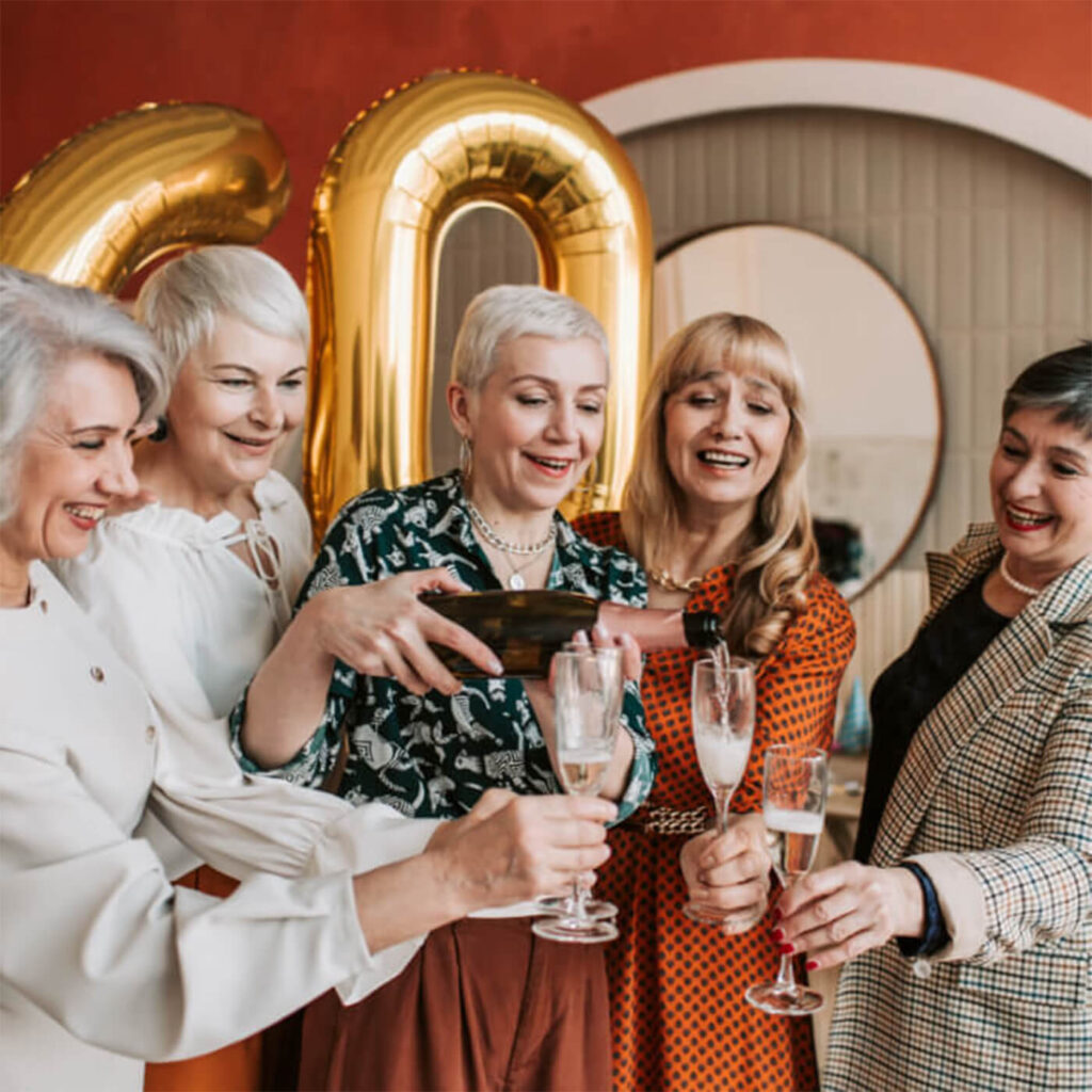 Older Women pouring champagne in front of balloons