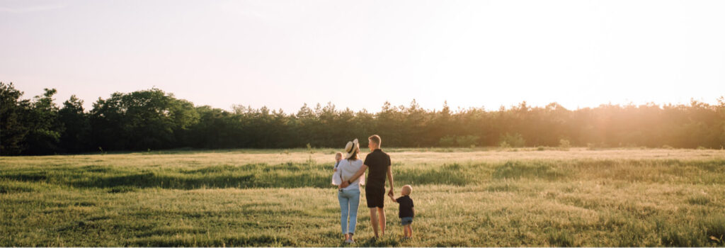 Couple with children in a field at sunset